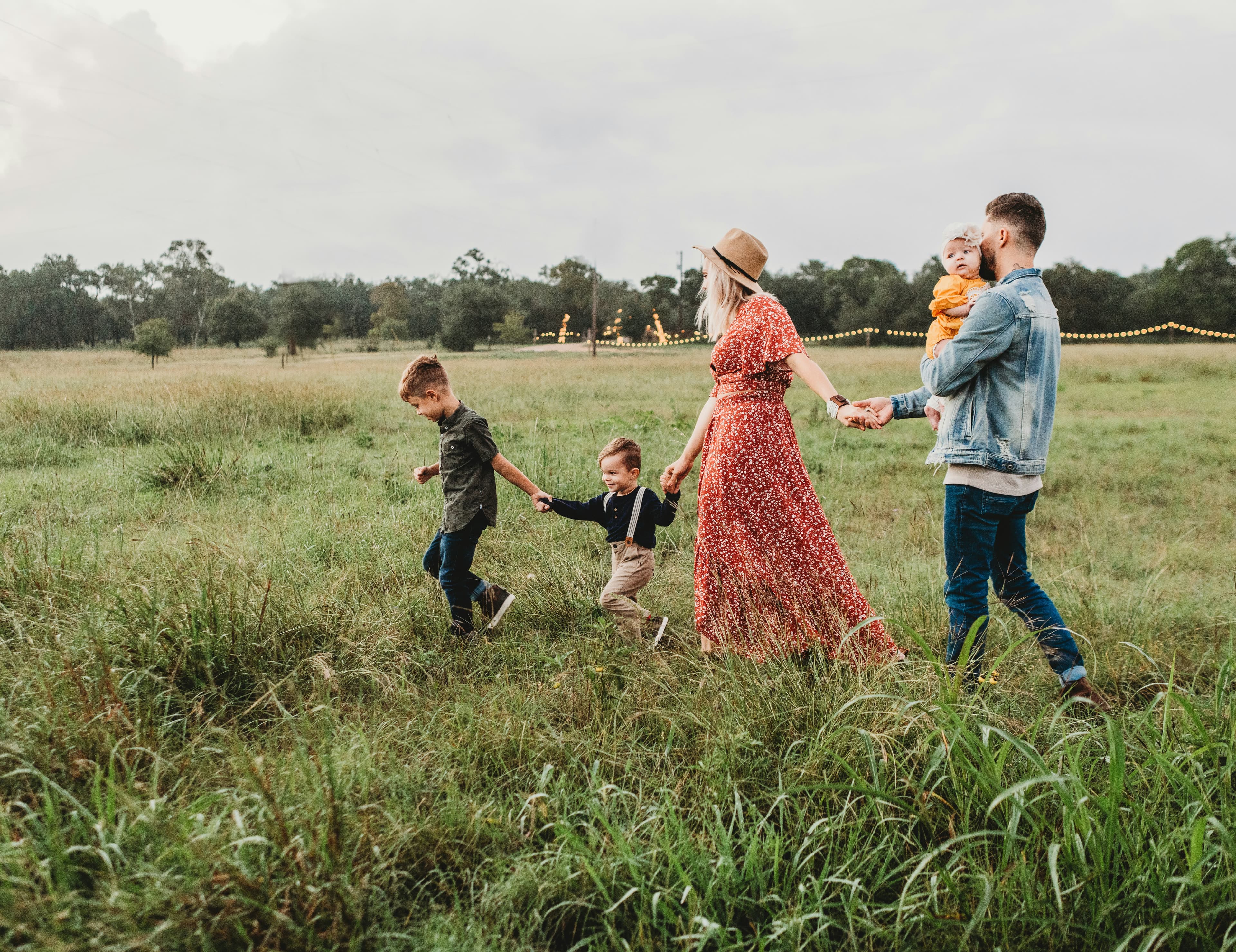 A young family walking together hand in hand across an open field